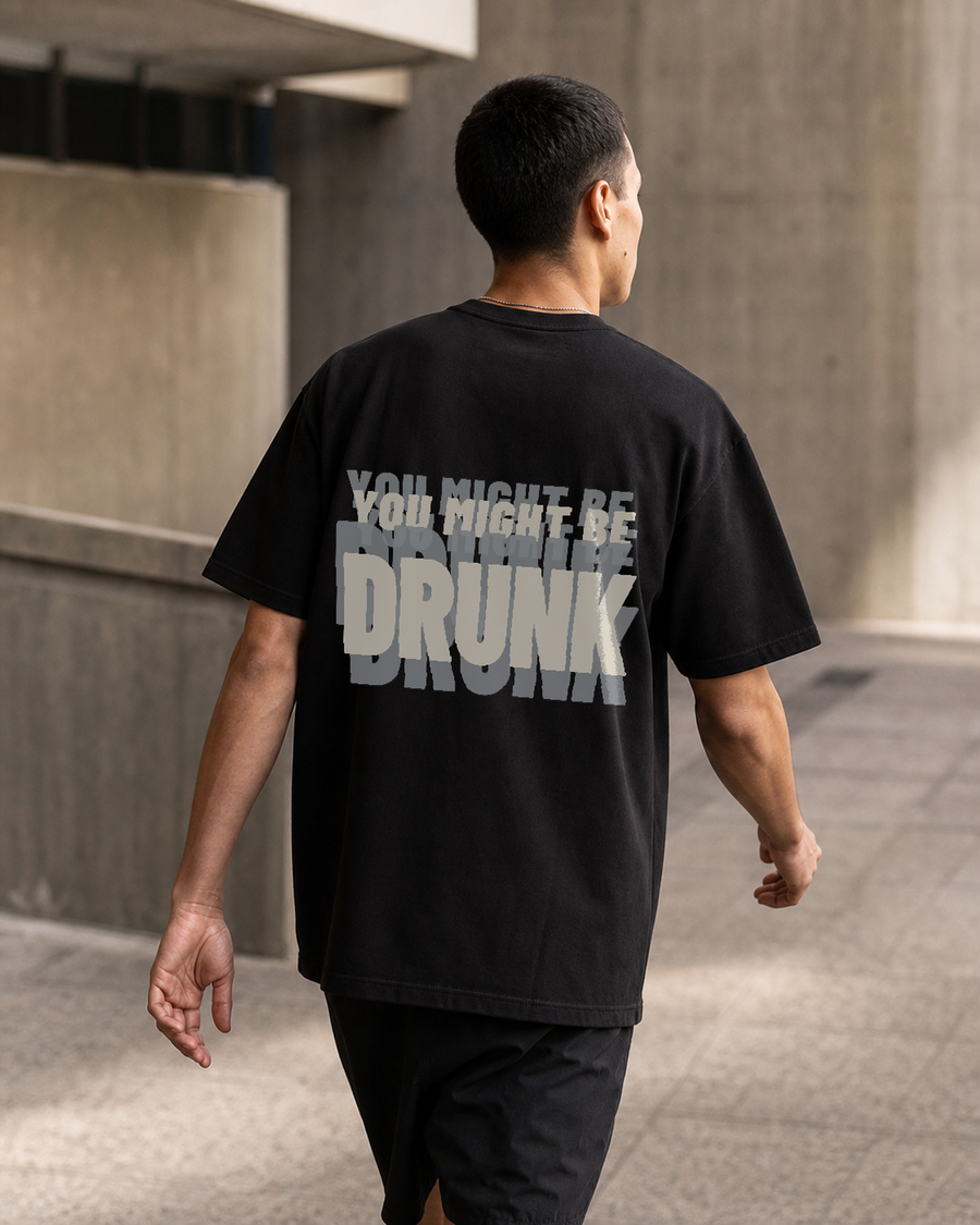 Rear view of a model wearing a black Retro-Futurism tee with the layered phrase “YOU MIGHT BE DRUNK” printed across the upper back.