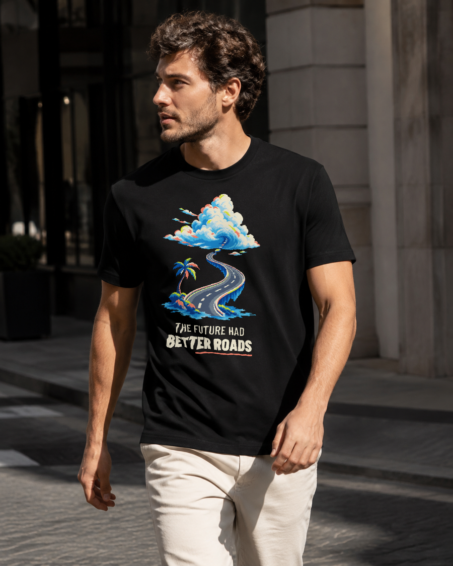 Three-quarter view of a model wearing the Black The Future Had Better Roads Tee with the pixel-art coastal-road graphic centered on the front.